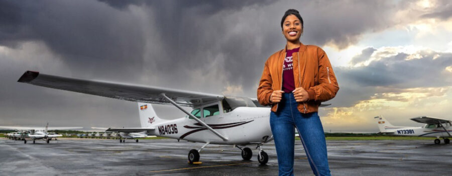 A young woman stands in front of a small plane